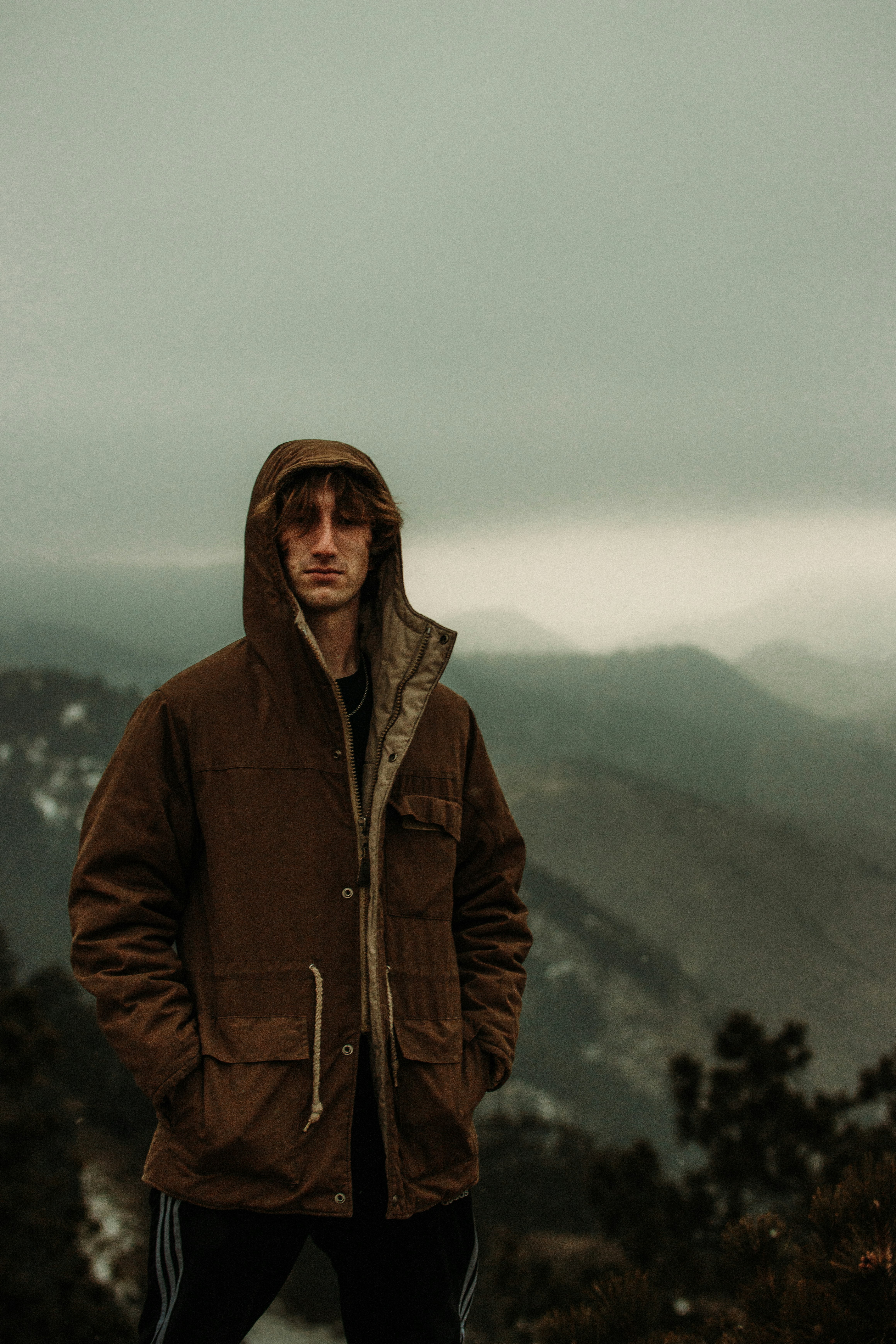 woman in brown zip up jacket standing on mountain during daytime